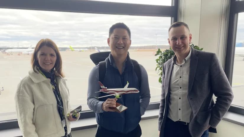 Belli team members meeting with an airline partner at an airport, holding a model aircraft.