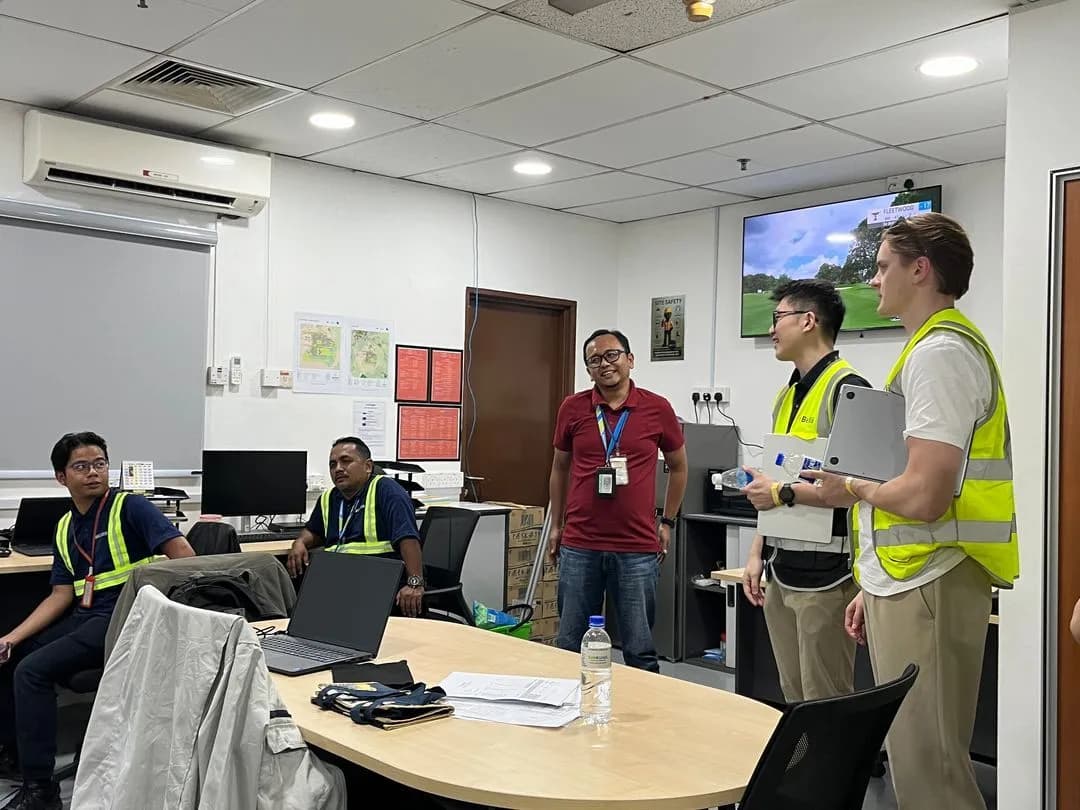 Two associates presenting from laptops in a customer's operations office