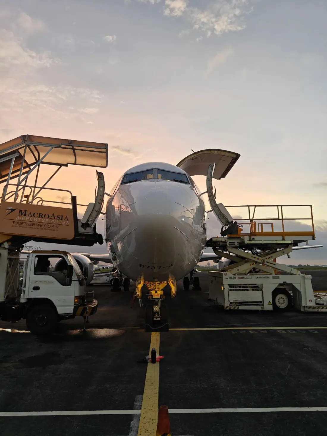 A Boeing 737 freighter on stand at dusk with its nose cargo door raised