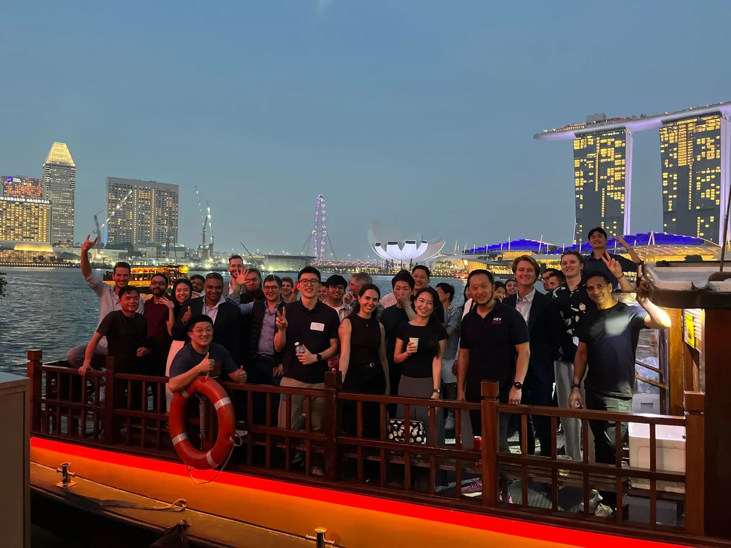 The Belli team on a boat in front of the Singapore skyline at night